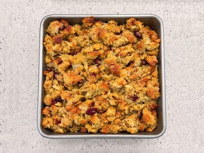 Baked apple and cranberry dressing, dotted with dried cranberries, in a square pan